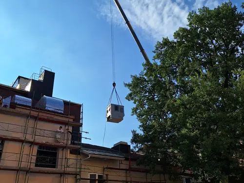 Der Kran befördert die Trafostation auf die andere Seite des Wohnhauses