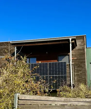 PV-Modul an einem Balkon an einem Holzhaus.