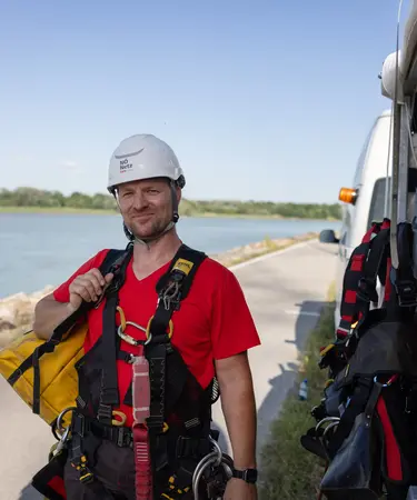 Netz NÖ Mitarbeiter mit Klettergut und Werkzeug. Im Hintergrund die Donau.