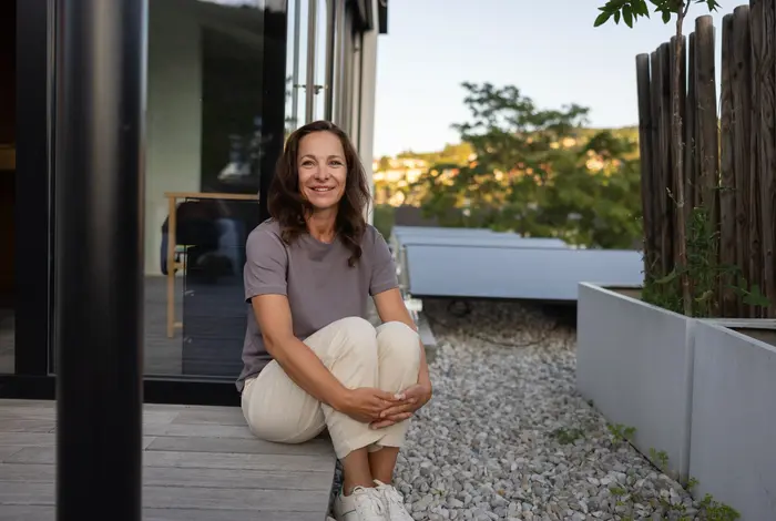 Frau sitzt auf Terrasse vor PV-Anlage.