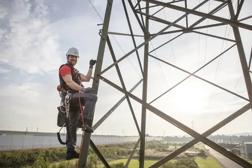 Ein Mitarbeiter arbeitet auf einem Strommast