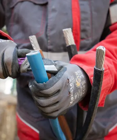Hände eines Netz NÖ Monteur, der mit einer Zange an einem Kabel arbeitet.