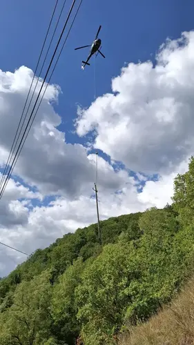 Helikopter fliegt mit Holzmasten.