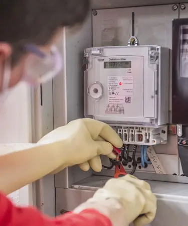 Netz NÖ Monteur mit Schutzhandschuhen und Werkzeug beim Zählertausch.