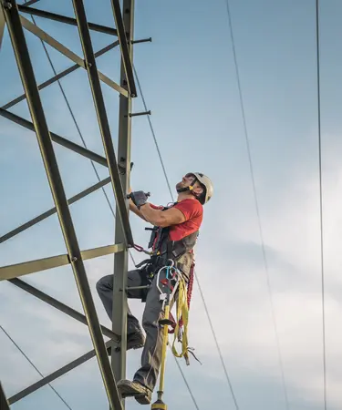 Symbolfoto eines Mitarbeiters, der auf einem Mast arbeitet