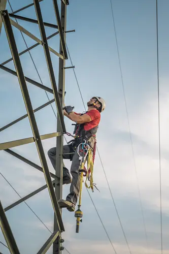 Symbolfoto eines Mitarbeiters, der auf einem Mast arbeitet