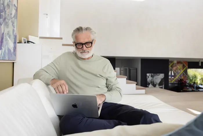 Älterer Mann auf Sofa mit Loptop