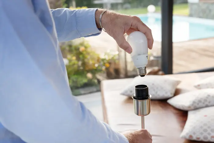 Mann schraubt Glühbirne in Fassung