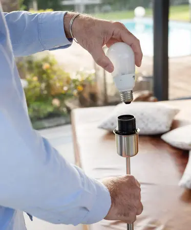 Mann schraubt Glühbirne in Fassung