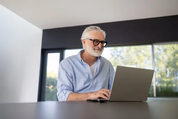 An Tisch sitzender Kunde blickt auf seinen Laptop - Banner