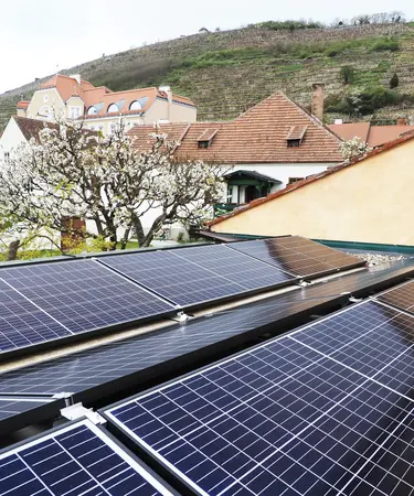 PV-Anlage auf einem Hausdach vor einer frühlingshaft blühenden Landschaft.