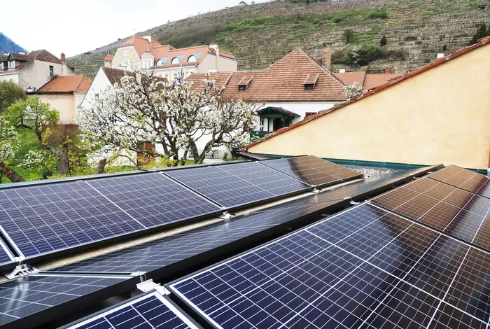 PV-Anlage auf einem Hausdach vor einer frühlingshaft blühenden Landschaft.