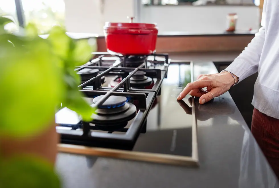 Frau steht am Gasherd.