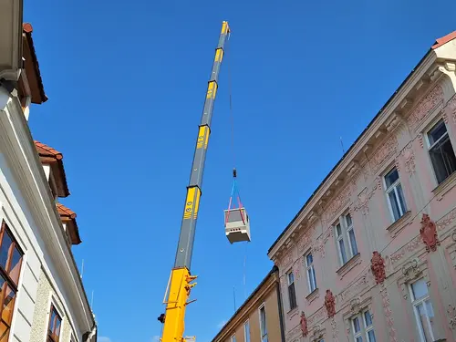 Eine neue Trafostation wird mittels Kran über ein Wohnhaus gehoben