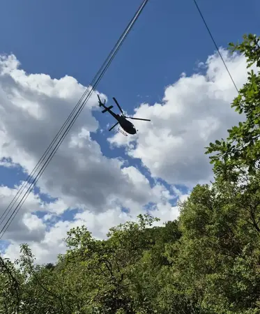 Helikopter fliegt bei Stromleitung.