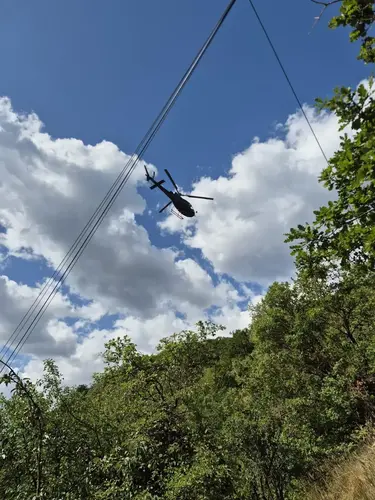Helikopter fliegt bei Stromleitung.