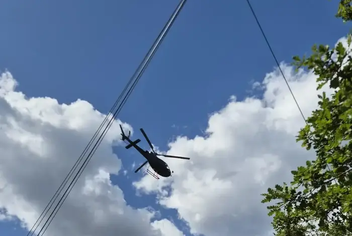 Helikopter fliegt bei Stromleitung.