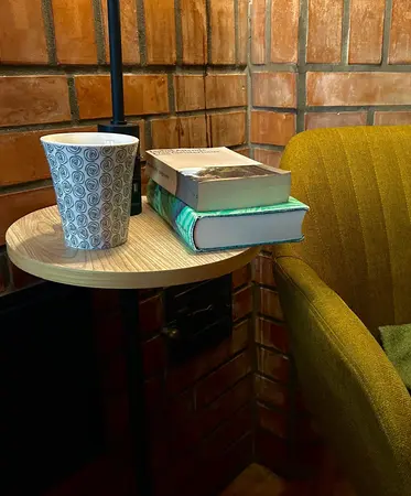 Gemütlicher Lesesessel; am Tischchen liegen Büchern und Tee.