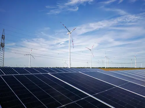 Groß-PV-Anlage mit Windrädern im Hintergrund