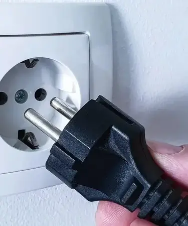 Ein Stecker wird in eine Steckdose gesteckt