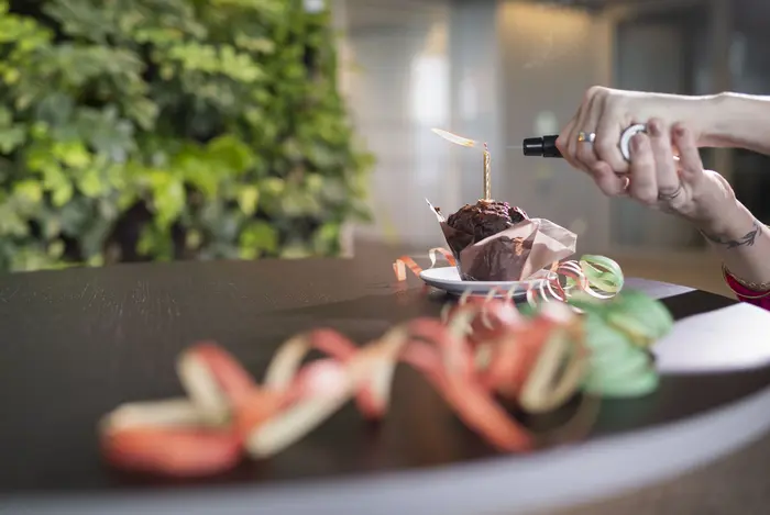 Muffin mit Geburtstagskerze, die mit Bunsenbrenner angezündet wird.