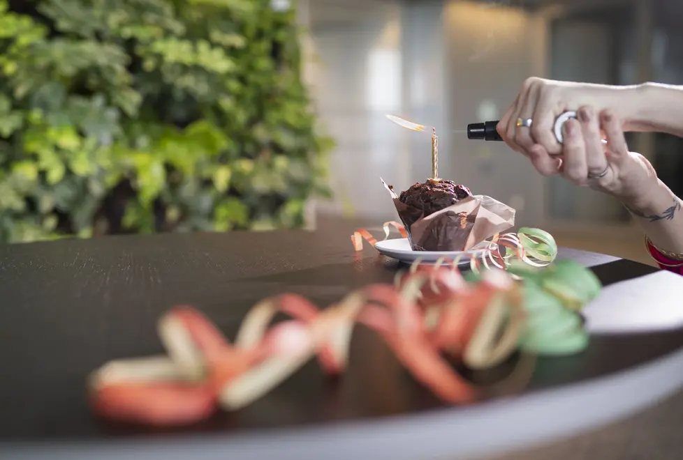 Muffin mit Geburtstagskerze, die mit Bunsenbrenner angezündet wird.