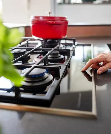 Frau steht am Gasherd.