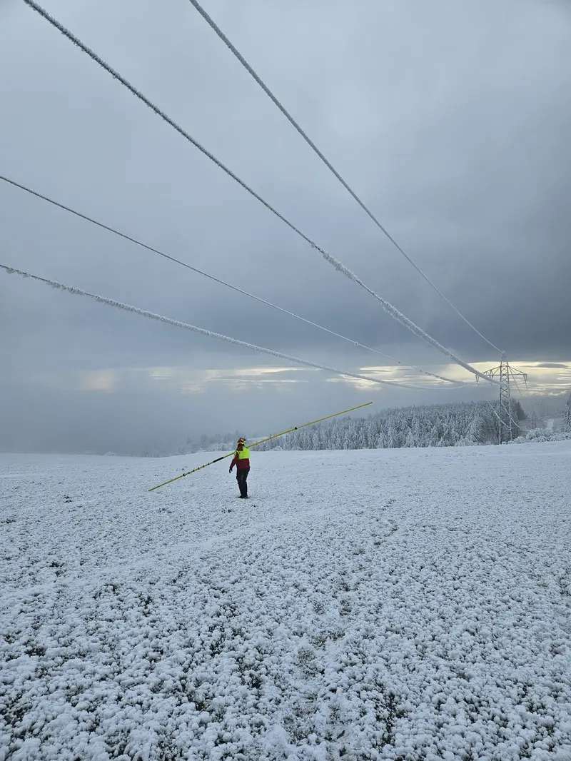 Netz NÖ Mitarbeiter klopft Eis von Leitungen ab.